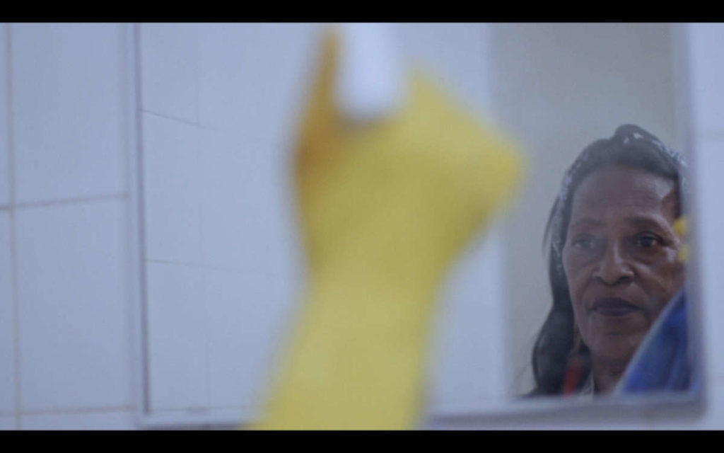 Woman with yellow gloves cleaning a mirror