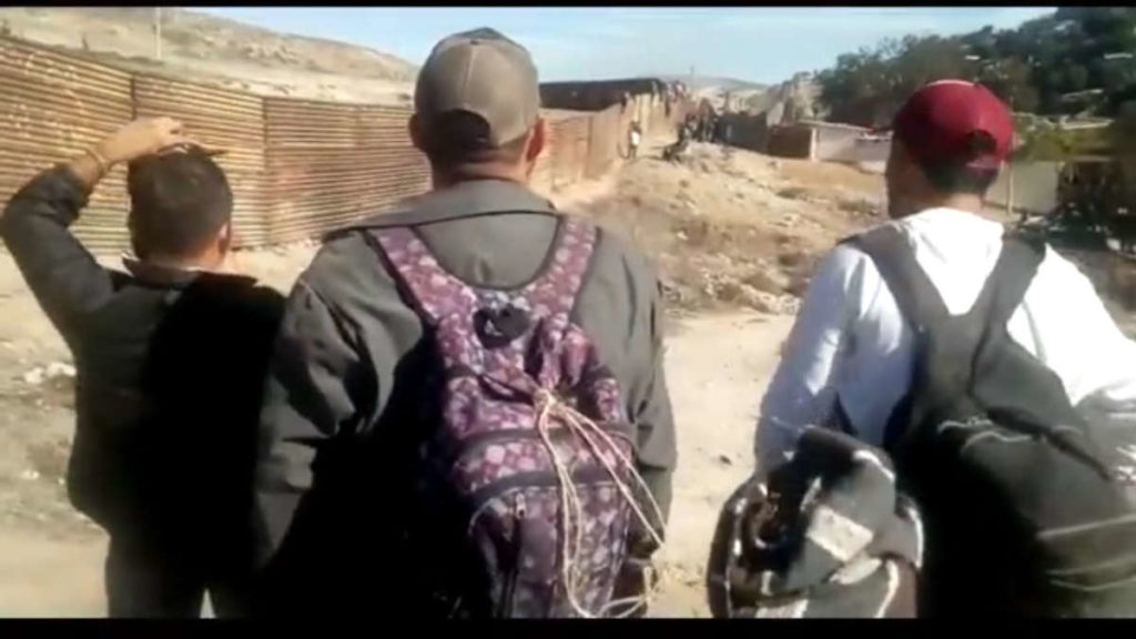 Immigrants looking at the border between Mexico and US